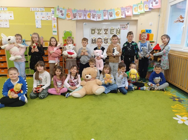 dzieci stoi w sali przedszkolnej, każde trzyma swojego pluszowego misia