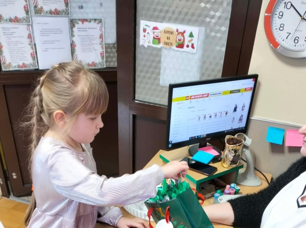 Dziewczynka losuje nagrodę (zakładkę do książki) za wykonanie wszystkich zadań.