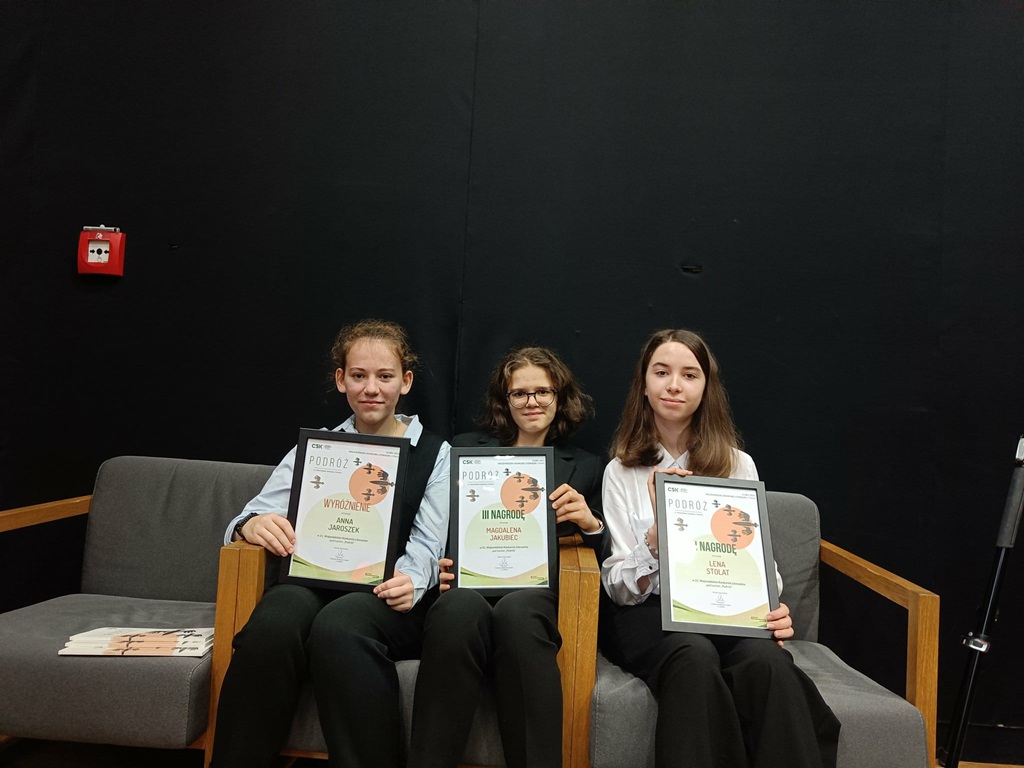 laureatki siedzą na fotelach i pokazują dyplomy.