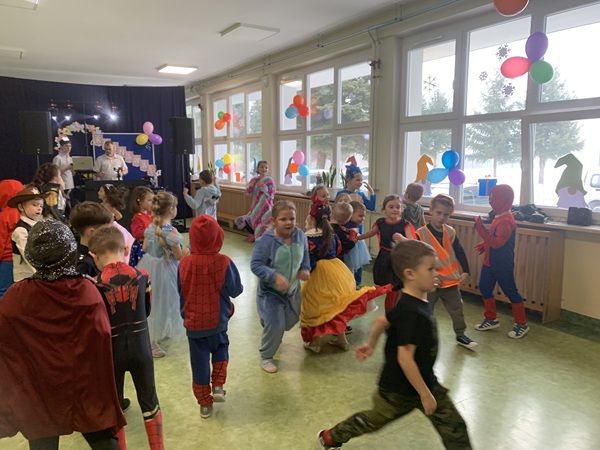 Dzieci w kolorowych strojach tańczą podczas balu karnawałowego.
