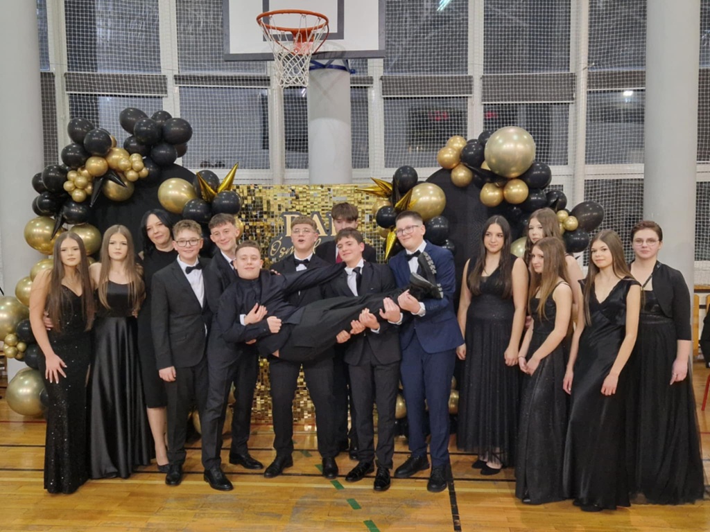 Klasa VIIIF z wychowawczynią, wszyscy w strojach balowych, ustawieni pod dekoracją.