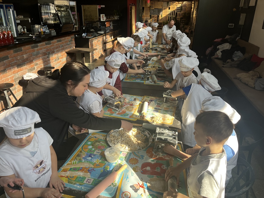 Uczniowie kl.2a siedzą w restauracji i własnoręcznie wykonują makaron w restauracji Franco.