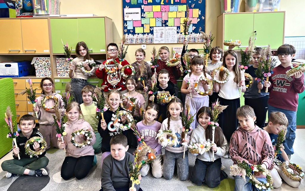 Uczestnicy warsztatów wielkanocnych. Dzieci trzymają palmy oraz wianki wielkanocne.