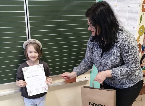 Nauczycielka wręcza dyplom i upominek laureatce konkursu.