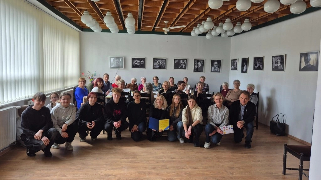 spotkanie wielkanocne z Klubem 50 PLUS: wolontariusze i seniorzy pozują do pamiątkowego zdjęcia