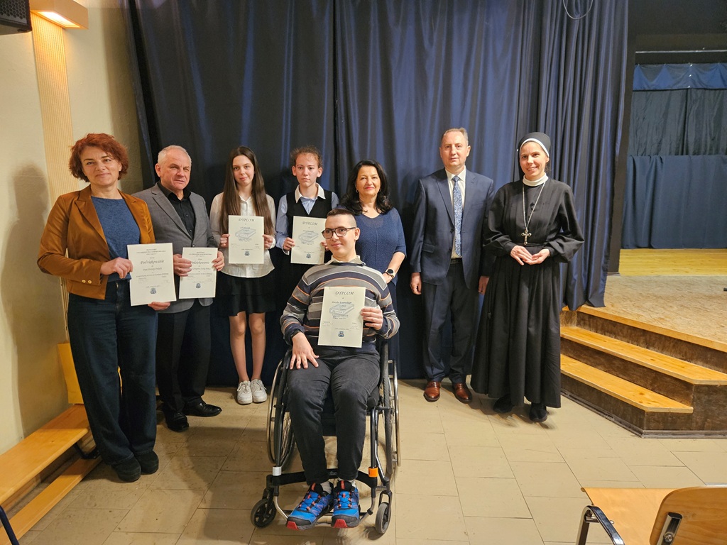 laureaci konkursu z dyplomami, na środku chłopiec na wózku inwalidzkim