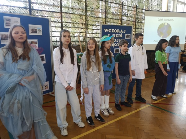 uczniowie klas 4 i 5 na tle dekoracji podczas występu z okazji Dnia Ziemi”