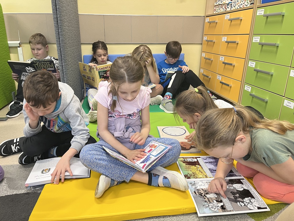 uczniowie klasy 2a, czytają książki w klasie na dywanie