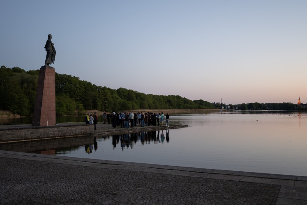 uczestnicy stoją pod pomnikiem „Niosącej”