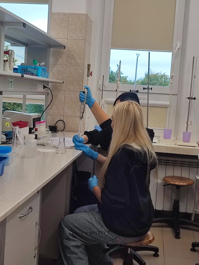 Dwie uczennice w laboratorium wykonują doświadczenie z próbówką.
