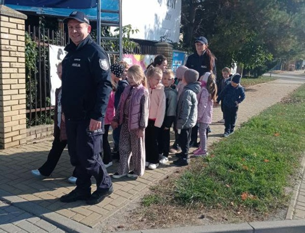2 policjantów i grupa uczniów stojących na chodniku