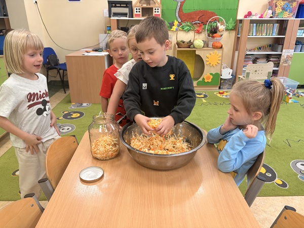 chłopiec wkłada posiekaną kapustę do słoika.