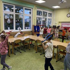 Dzieci z szarfami uniesionymi na wyprostowanych rękach nad głową