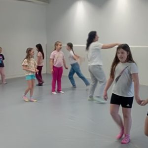 Grupa dzieci w strojach sportowych, które ćwiczą.
