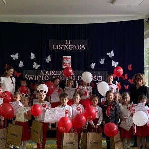 Duża grupa dzieci z balonami biało-czerwonymi.