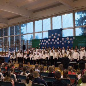 Szkolny chór stoi na tle świątecznej scenografii w budynku przy ulicy Szkolnej 53.