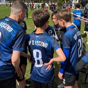 chłopcy stoją razem na boisku czekają na bieg i słuchają wskazówek nauczyciela.