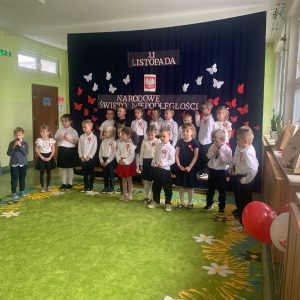 Grupa dzieci ustawiona w dwóch rzędach na granatowym tle.