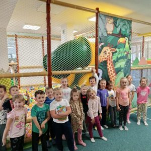 Grupa dzieci ustawiona do pamiątkowego zdjęcia, w tle kolorowych zjeżdżalni i kulek do skakania