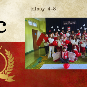 grupa najmłodszych uczniów w biało-czerwonych strojach prezentuje patriotyczne prace i trzyma polskie flagi.