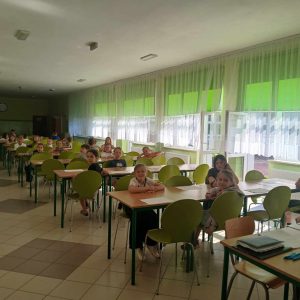 grupa uczniów reprezentujących klasy 3 i 2, piszących test konkursowy na stołówce szkolnej.
