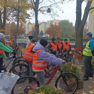 uczniowie siedzą na rowerach i słuchają instruktażu osoby dorosłej