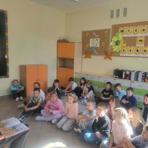 uczniowie słuchają czytania starszej koleżanki.