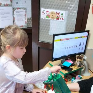 Dziewczynka losuje nagrodę (zakładkę do książki) za wykonanie wszystkich zadań.