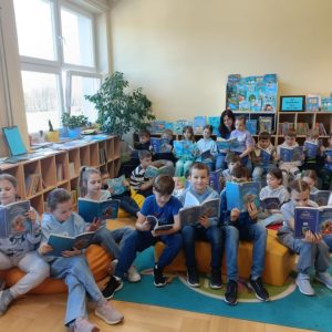 3E z nauczycielem, jednocząca się z osobami z Autyzmem – dzieci ubrane na niebiesko, czytają książki z niebieskimi okładkami.