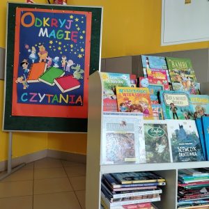 Wystawka podarowanych książek, w tle plakat pt. Odkryj magię czytania