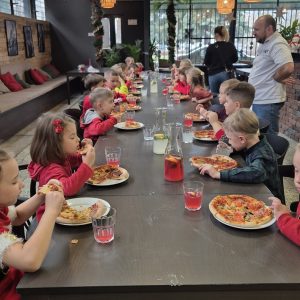 Dzieci z apetytem degustują przygotowane przez siebie pizze