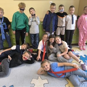 grupa uśmiechniętych uczniów w krawatach, muszkach z imitacją wąsów