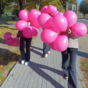 trzy dziewczyny idą, trzymają różowe balony, w tle jesienne drzewa