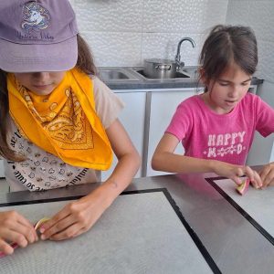 dwie dziewczynki wykonują lizaki w manufakturze słodyczy.
