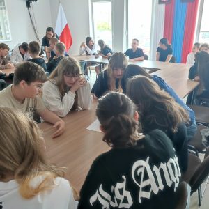Uczniowie przy stolikach rozwiązujący zadania