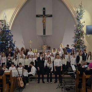 Churzyści w białych koszulach i czarnych spodniach. Z przodu troje wykonują jeden z utworów.