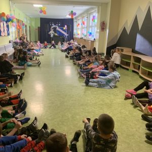 Dzieci siedzą na podłodze z biorąc udział we wspólnej zabawie.