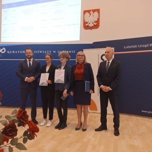 uczniowie naszej szkoły z panią dyrektor stoją z dyplomami, obok przedstawiciele kuratorium