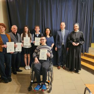laureaci konkursu z dyplomami, na środku chłopiec na wózku inwalidzkim