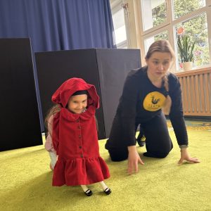 dziewczynka przebrana za Czerwonego Kapturka, a obok kobieta prowadząca zajęcia.