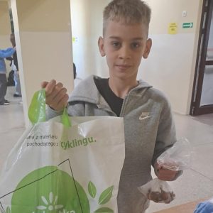 Chłopiec trzymający worek na wadze i woreczek z cebulkami kwiatów.