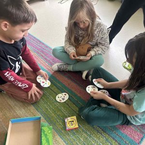 Dziewczynki grają z chłopcem w Dobble.