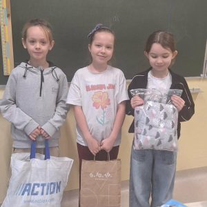 Dzieci trzymają w rękach torby, w których znajdują się artykuły dla zwierząt.