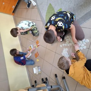 Dziewczynka gra z chłopcem. Dwaj chłopcy układają kafelki z obrazkami.