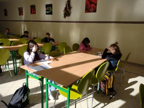 Uczniowie przy stolikach rozwiązują test konkursowy